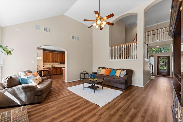 living area featuring a ceiling fan, dark wood-style floors, visible vents, and arched walkways