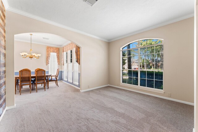 carpeted dining room with visible vents, arched walkways, an inviting chandelier, crown molding, and baseboards