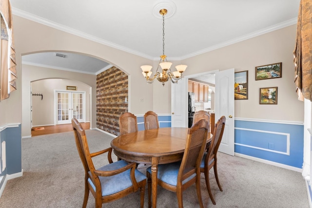 dining space featuring visible vents, arched walkways, light colored carpet, and a chandelier