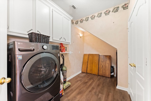 washroom featuring visible vents, washer / clothes dryer, wood finished floors, cabinet space, and baseboards