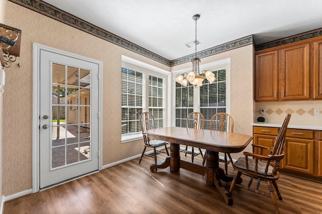 dining room with baseboards, a notable chandelier, dark wood-style flooring, and wallpapered walls