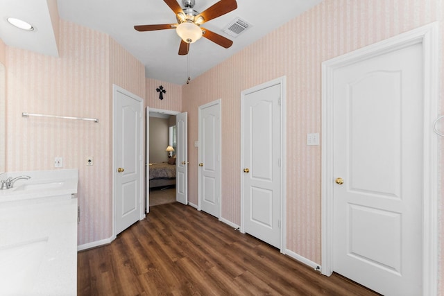 unfurnished bedroom with a sink, visible vents, and wallpapered walls