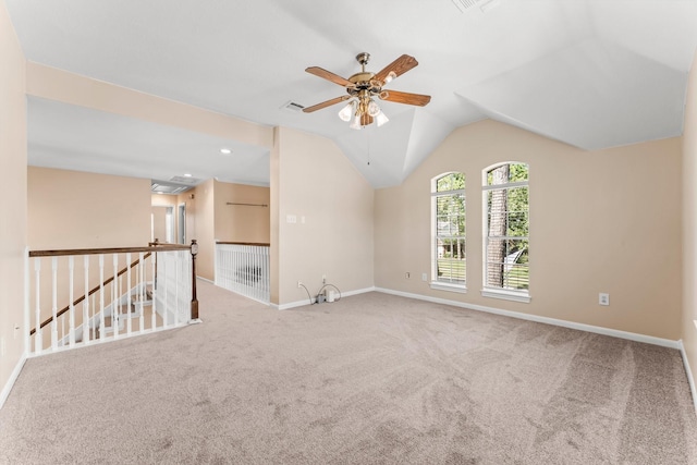 carpeted spare room with vaulted ceiling, a ceiling fan, and baseboards