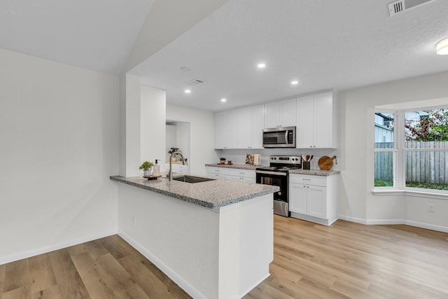 kitchen featuring visible vents, light wood-style flooring, a sink, light stone counters, and stainless steel appliances