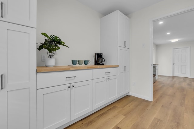 interior space with wooden counters, baseboards, light wood-style flooring, and white cabinetry