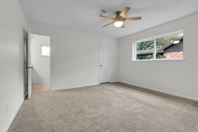 carpeted empty room with baseboards, visible vents, a textured ceiling, and ceiling fan