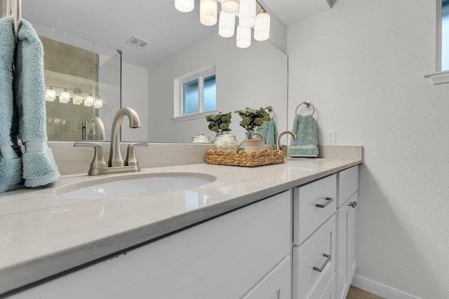 full bath with a sink, visible vents, a stall shower, and double vanity