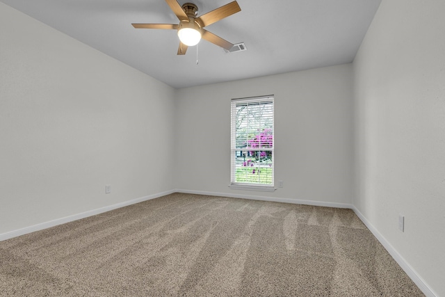 empty room with carpet, visible vents, a ceiling fan, and baseboards