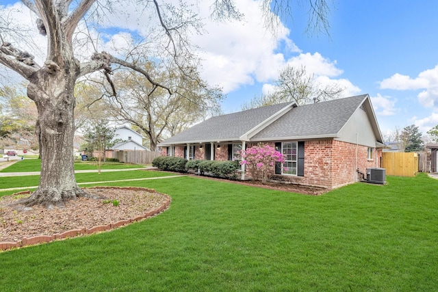 exterior space with central air condition unit, brick siding, a yard, and fence