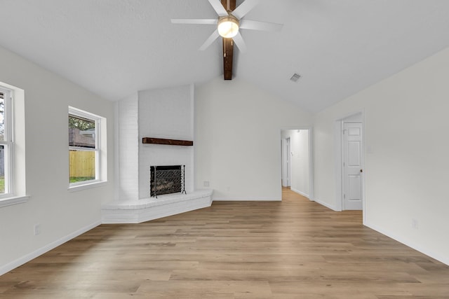 unfurnished living room with light wood-type flooring, a ceiling fan, a fireplace, baseboards, and vaulted ceiling with beams