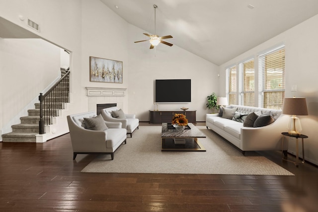 living room featuring stairway, high vaulted ceiling, ceiling fan, hardwood / wood-style flooring, and a tiled fireplace