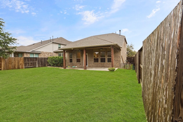 back of house featuring a yard, a patio area, brick siding, and a fenced backyard