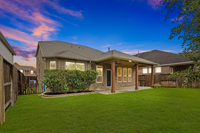 back of house with a yard, a patio, brick siding, and a fenced backyard