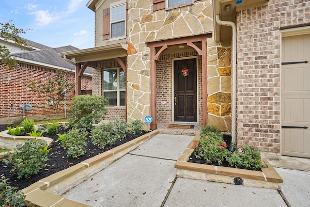 view of exterior entry featuring stone siding and brick siding