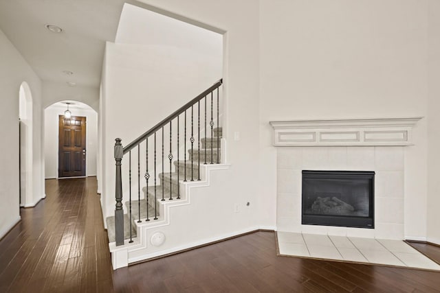 interior space featuring arched walkways, stairway, baseboards, and dark wood-style flooring