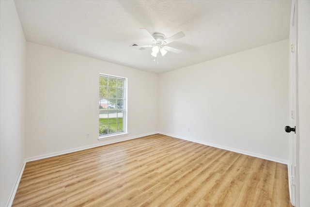 spare room featuring light wood-type flooring, baseboards, and ceiling fan