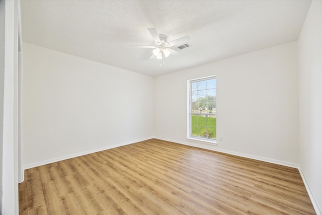 empty room with visible vents, a ceiling fan, a textured ceiling, light wood finished floors, and baseboards