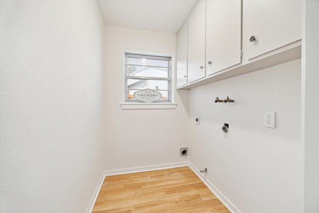 clothes washing area featuring baseboards, light wood-style floors, hookup for a gas dryer, cabinet space, and electric dryer hookup