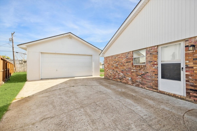 view of property exterior featuring brick siding, a garage, an outdoor structure, and fence