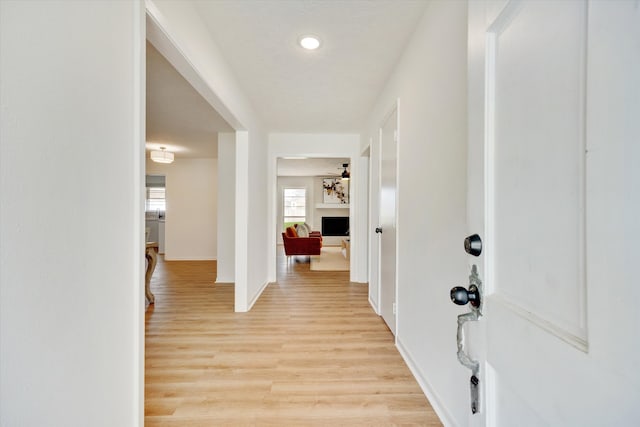 foyer entrance featuring a fireplace, baseboards, and light wood-style floors