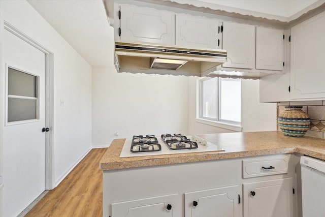 kitchen with under cabinet range hood, white appliances, and white cabinetry