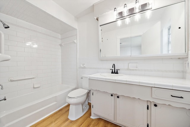 bathroom with toilet, wood finished floors, tile walls, bathing tub / shower combination, and vanity