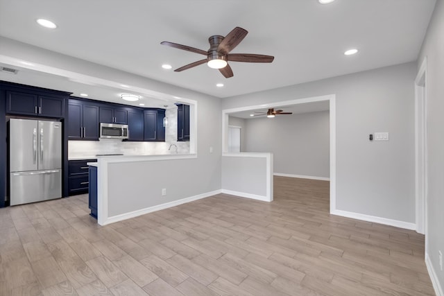 kitchen featuring light wood finished floors, blue cabinetry, ceiling fan, light countertops, and stainless steel appliances