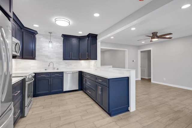 kitchen with blue cabinetry, backsplash, ceiling fan, a peninsula, and stainless steel appliances