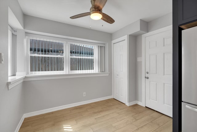 interior space featuring light wood-style floors, baseboards, and ceiling fan