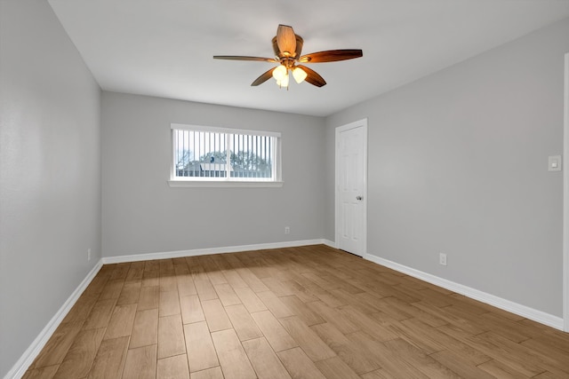 spare room with baseboards, light wood-style floors, and a ceiling fan