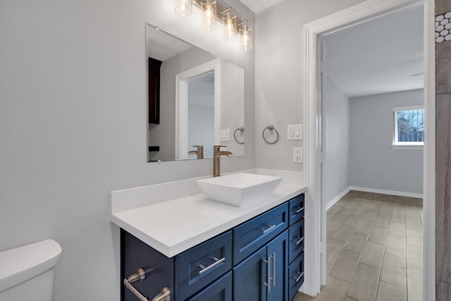 bathroom with vanity, toilet, and baseboards