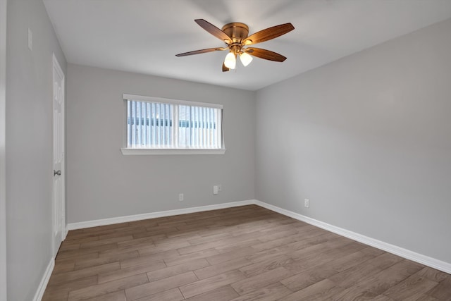 empty room with baseboards, wood finished floors, and a ceiling fan