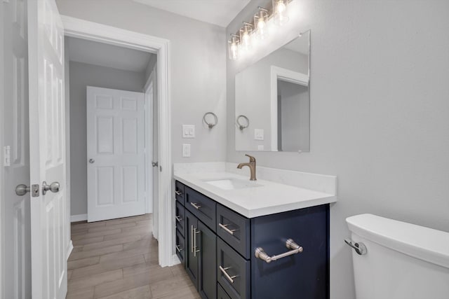 bathroom with wood finish floors, toilet, and vanity