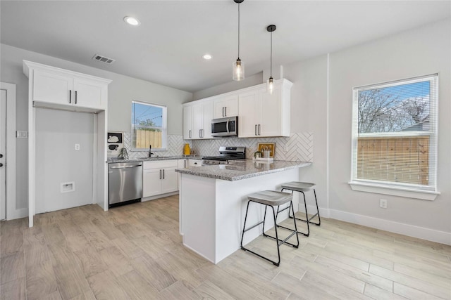 4715 Ward St, Houston, TX 77021 - kitchen featuring stainless steel appliances, white cabinetry, tasteful backsplash, a peninsula, and recessed lighting