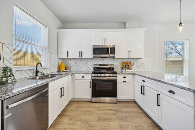 4715 Ward St, Houston, TX 77021 - kitchen featuring stainless steel appliances, a sink, white cabinets, and light wood-type flooring