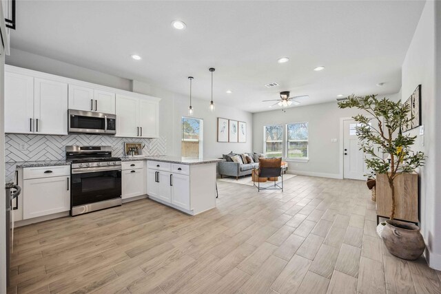 4715 Ward St, Houston, TX 77021 - kitchen with appliances with stainless steel finishes, open floor plan, a peninsula, tasteful backsplash, and white cabinetry