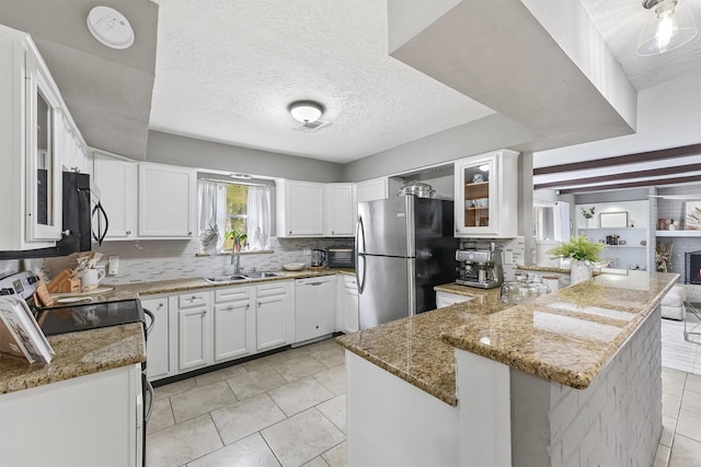 kitchen with light stone counters, dishwasher, freestanding refrigerator, and a sink