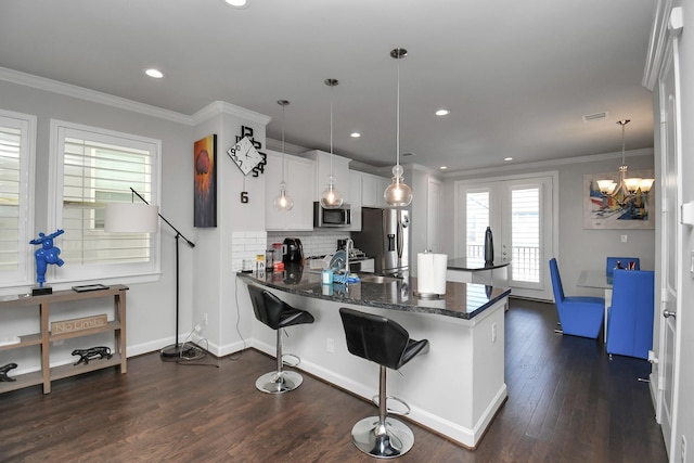 kitchen with ornamental molding, tasteful backsplash, dark wood finished floors, stainless steel appliances, and a peninsula