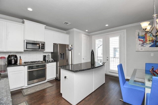 kitchen with visible vents, dark wood finished floors, ornamental molding, stainless steel appliances, and a chandelier