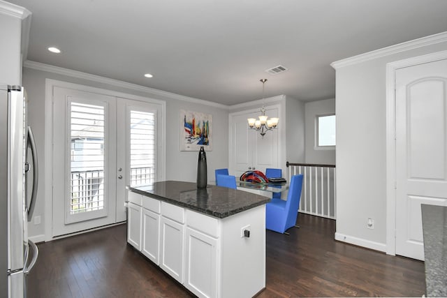 kitchen with an inviting chandelier, visible vents, freestanding refrigerator, and ornamental molding