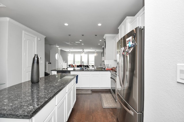 kitchen with dark wood finished floors, a peninsula, stainless steel appliances, white cabinets, and backsplash