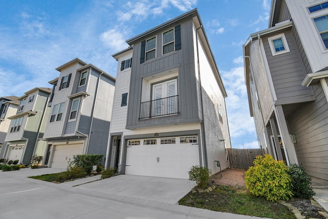 multi unit property with driveway, fence, board and batten siding, a garage, and a balcony