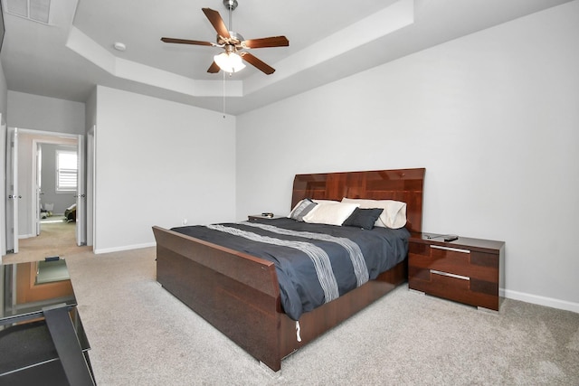 bedroom featuring a raised ceiling, carpet flooring, and baseboards