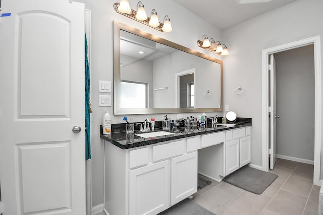 bathroom featuring a sink, baseboards, double vanity, and tile patterned flooring