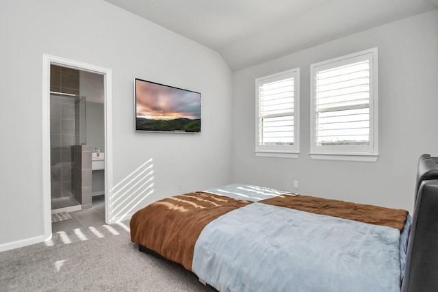 carpeted bedroom featuring ensuite bath and vaulted ceiling