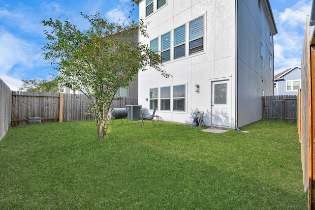 back of property featuring central air condition unit, a lawn, and a fenced backyard