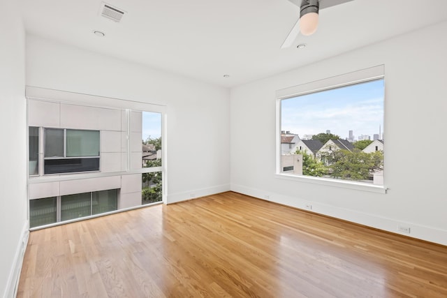 unfurnished living room featuring visible vents, a ceiling fan, baseboards, and wood finished floors