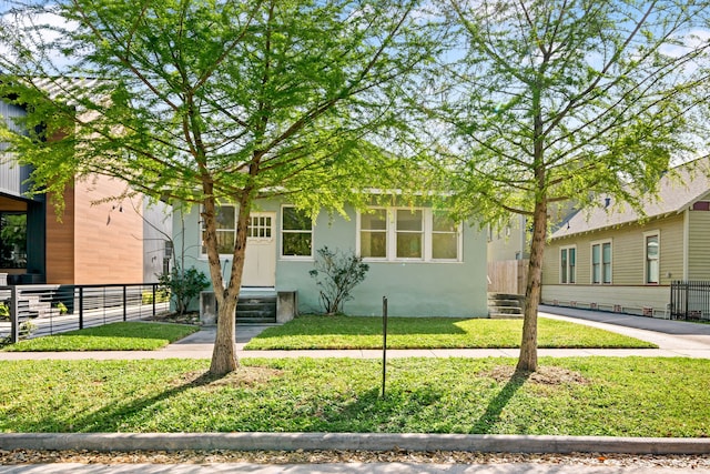 view of front of house featuring stucco siding, a front lawn, and fence