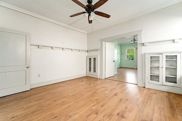 empty room with baseboards, a ceiling fan, light wood-style floors, and ornamental molding