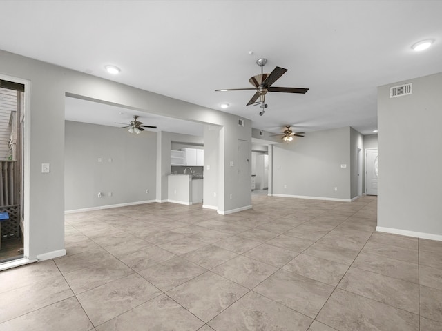 unfurnished living room with a ceiling fan, visible vents, and baseboards